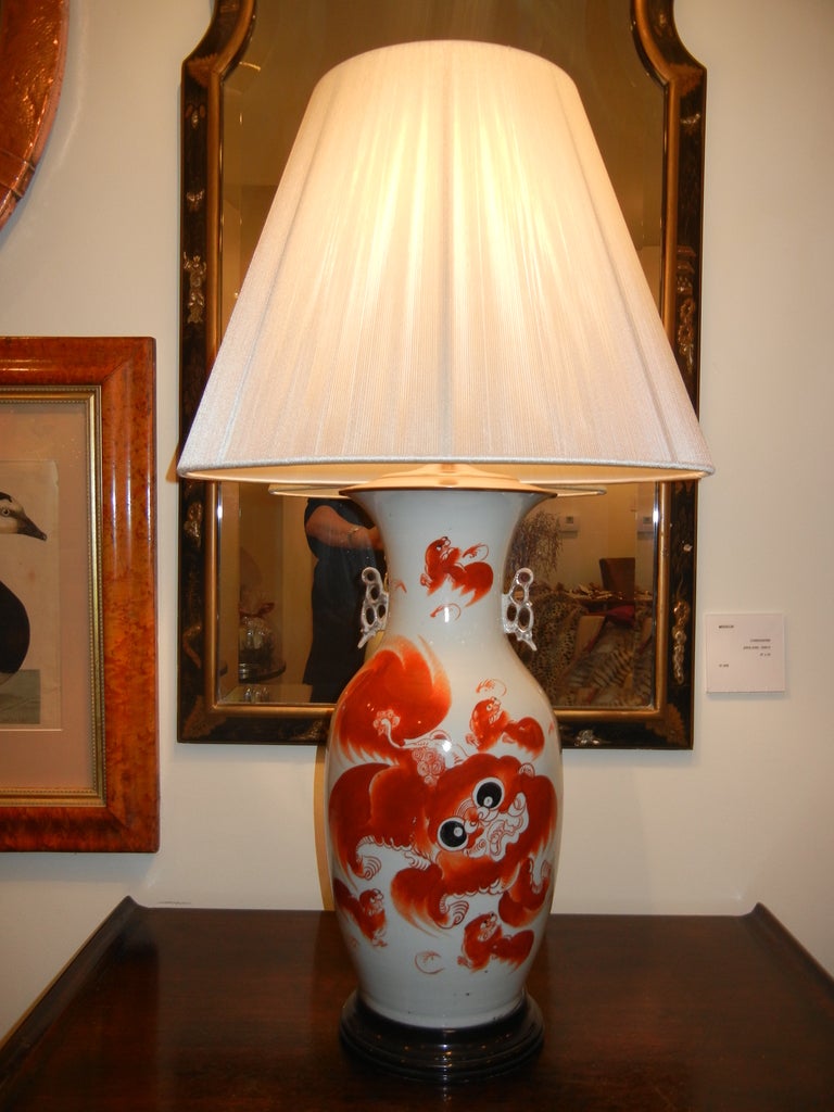 A Late 19th century ceramic vase turned into a table lamp. Bronze cap, new fittings and wire, three way on and off switch. A baby dragon painting in a wonderful orange red, large black eyes. Wooden carved out stand.

Hand crafted white string